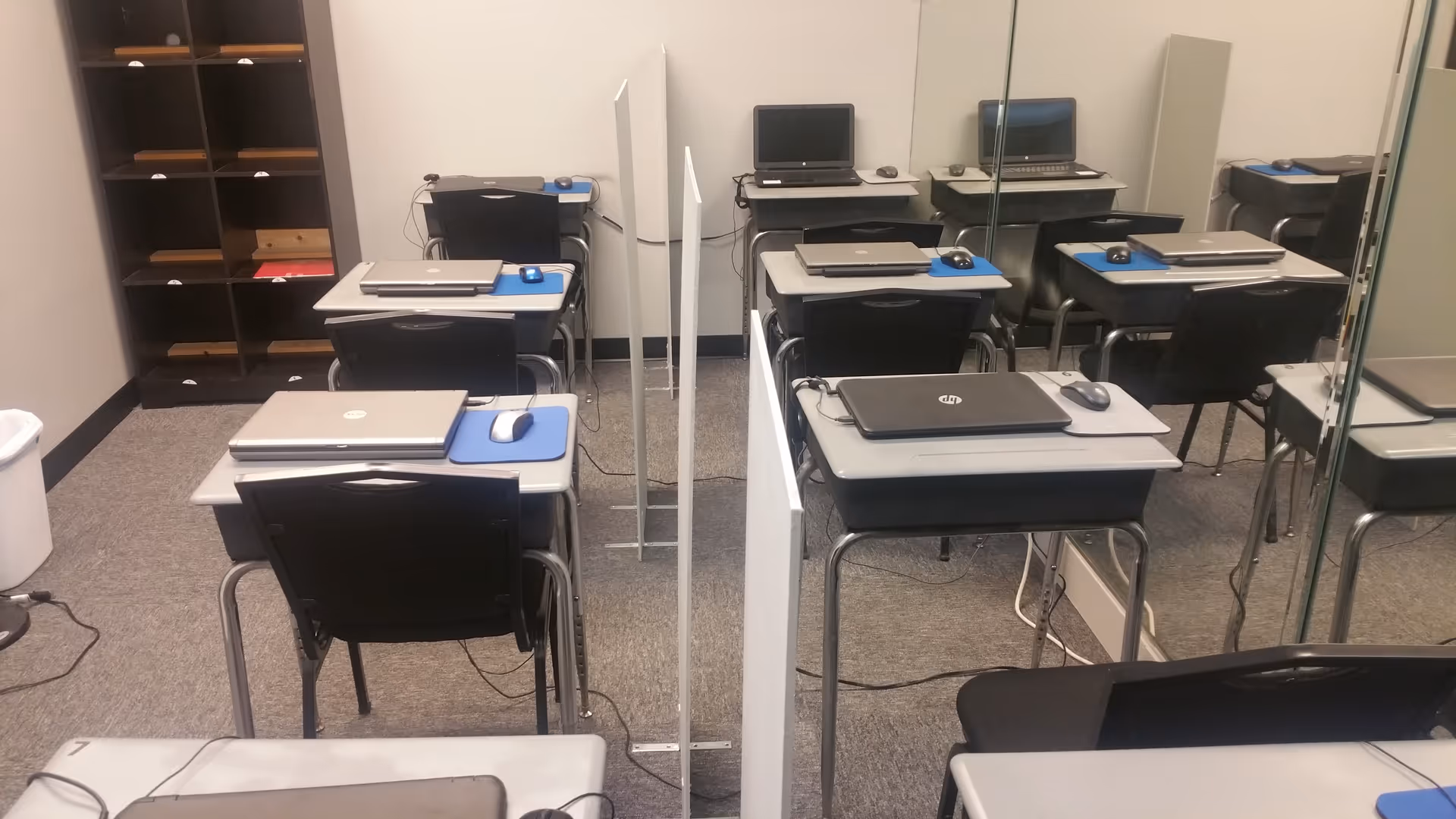 Classroom with desks, laptops, mice, and partition dividers in a training center