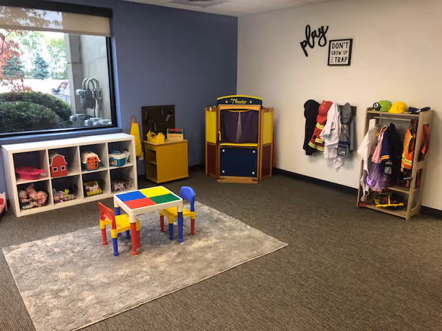 Colorful children's play area inside a senior living facility with toys and coats.
