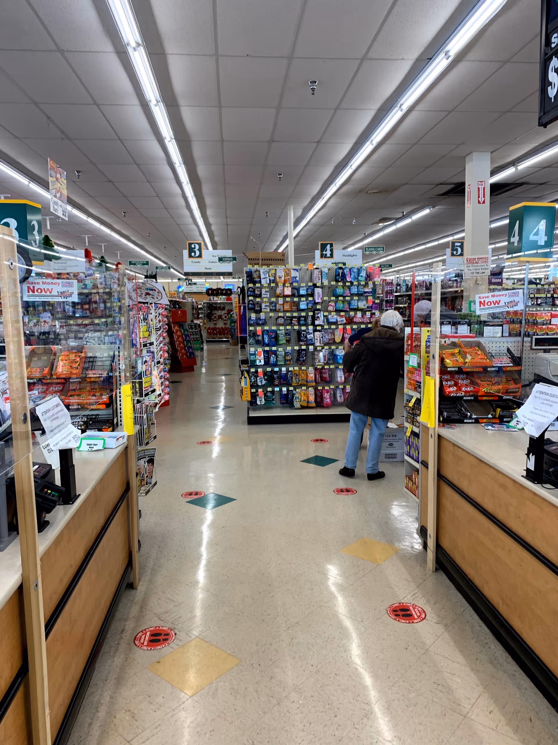 Inside Discount Drug Mart, aisles of products line the store while a shopper browses.