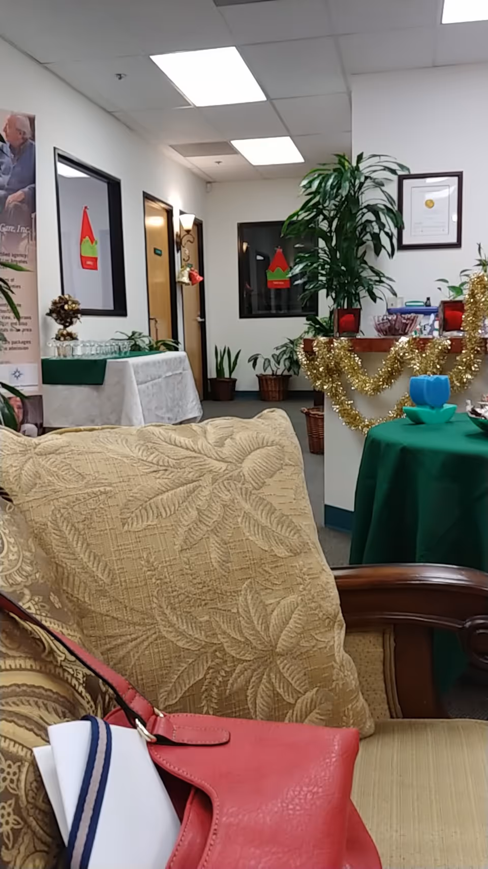 Indoor lounge area with beige patterned sofa, plants, and a decorated reception counter.
