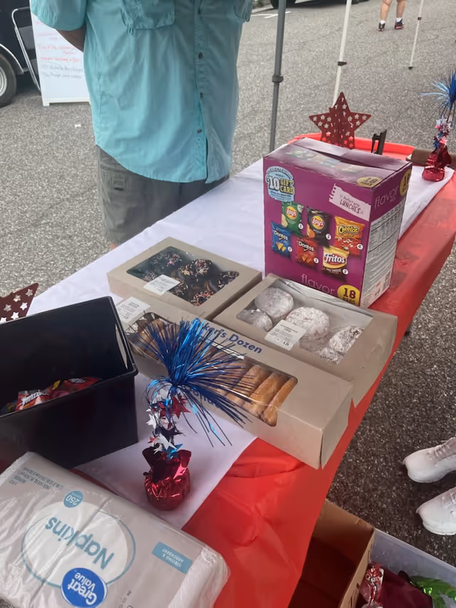 Outdoor table with assorted snacks and donuts at a booth.
