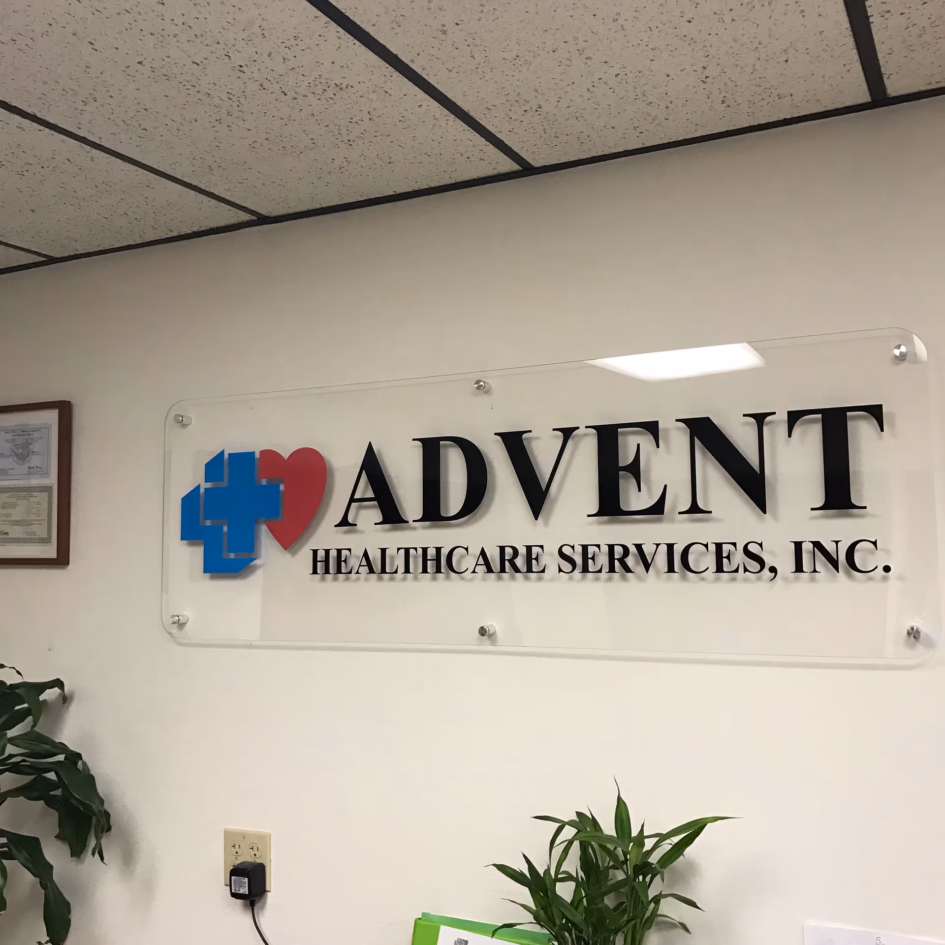 Indoor reception area with Advent Healthcare Services sign on the wall and plants.