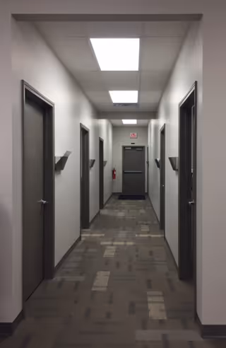 Long hallway in a senior living facility with multiple doors and ceiling lights.