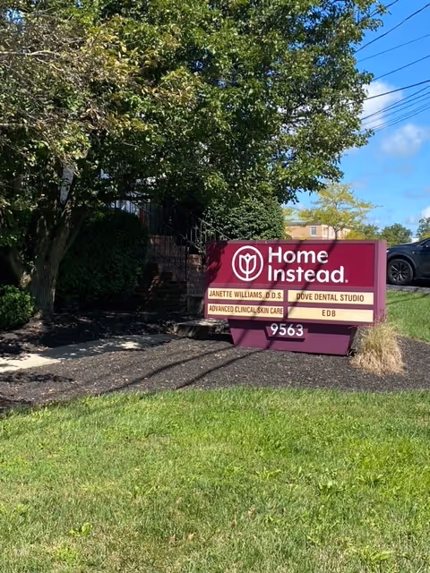 A Home Instead sign sits on a grassy area near the building entrance.