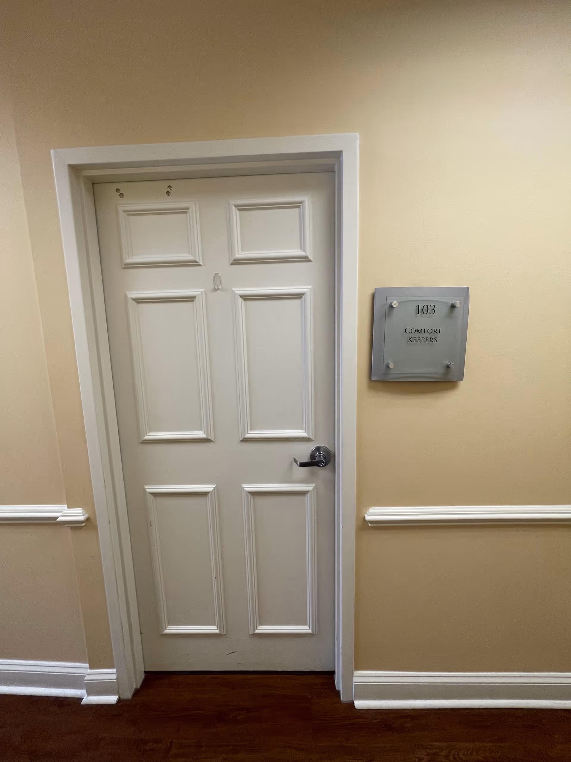 Interior hallway with a white door and plaque reading 103 Comfort Keepers.