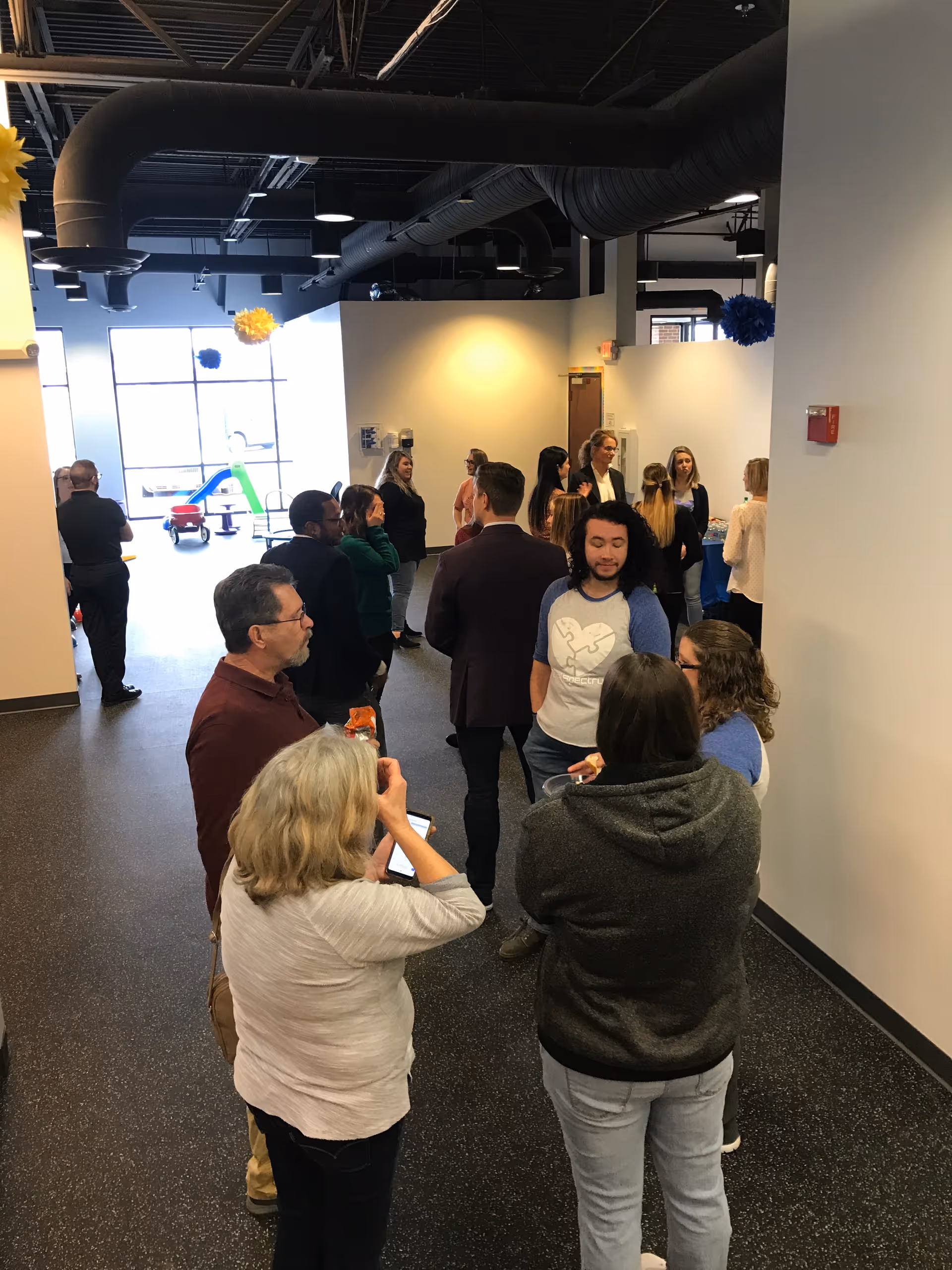 People mingle in a modern interior hallway during an open house event.