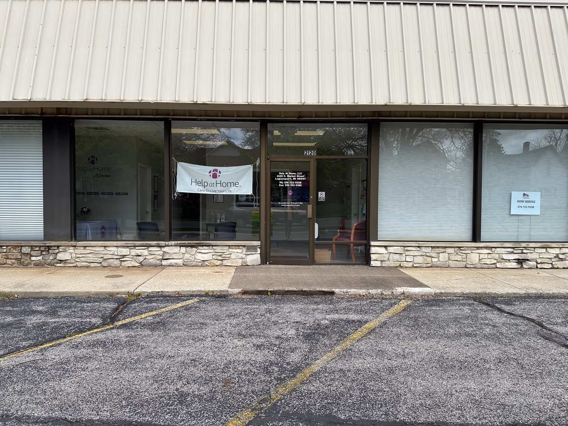 Front view of Help at Home facility with glass windows, banner, and stone facade