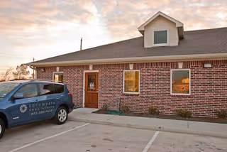 Brick exterior of Enhabit Home Health facility with a parked blue vehicle.