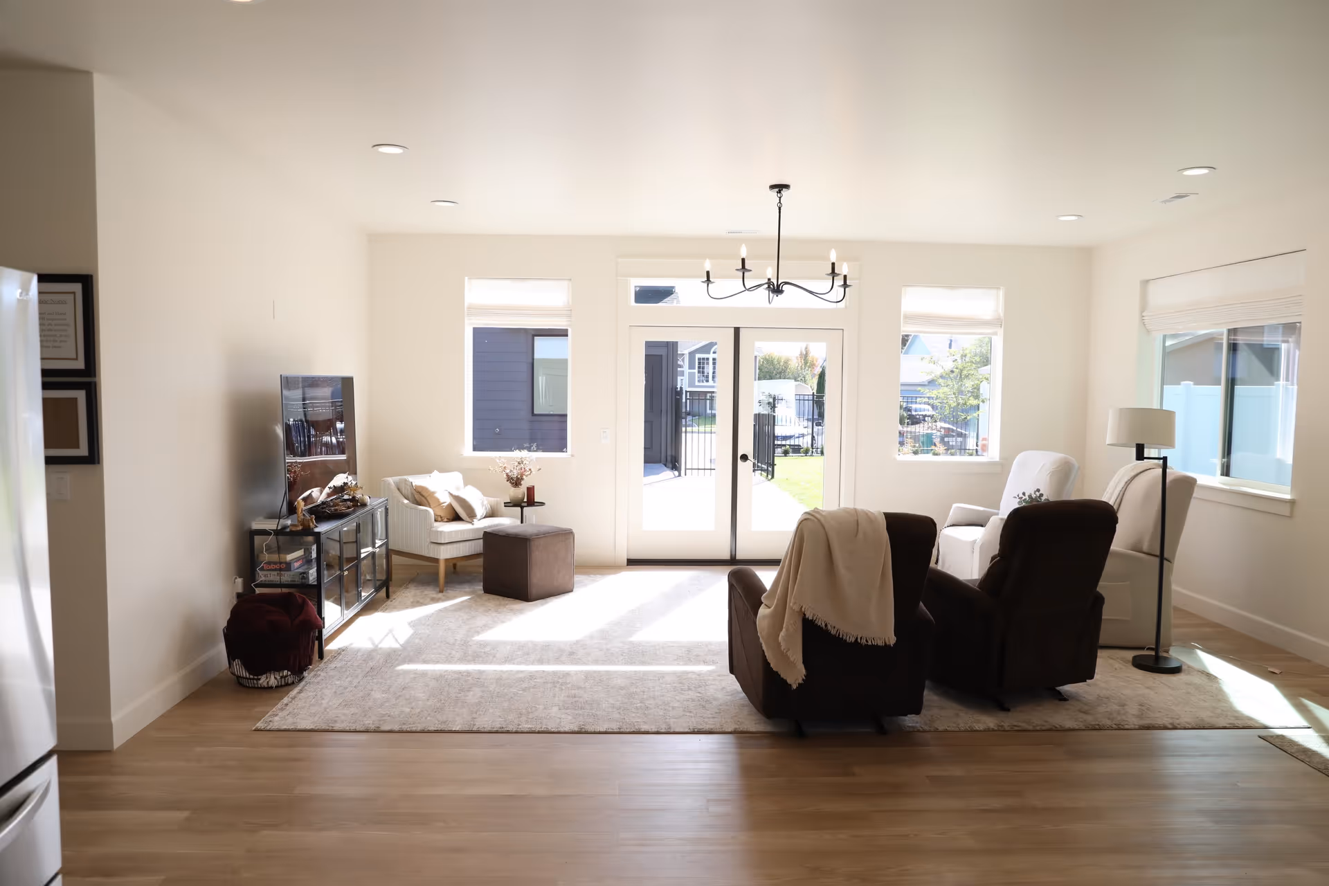 Bright, modern living room with seating area, TV stand, and glass doors to outside.