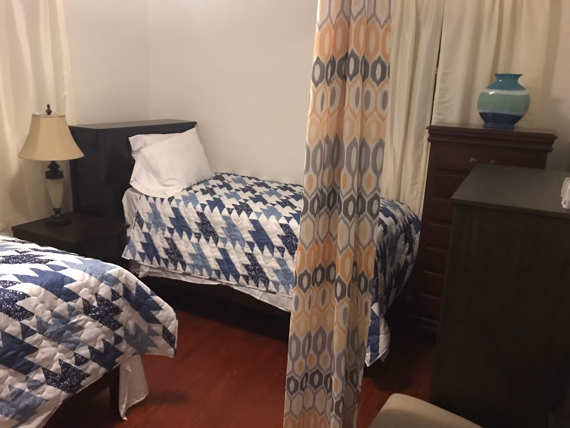 Two twin beds with patchwork blue quilts in a cozy shared bedroom.