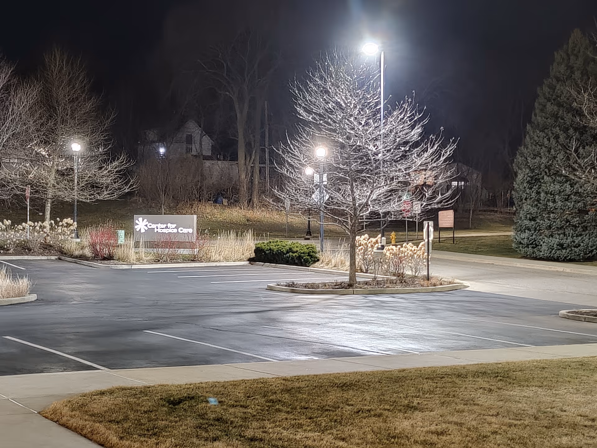 Night view of Center for Hospice Care exterior with dim parking lot and illuminated sign.
