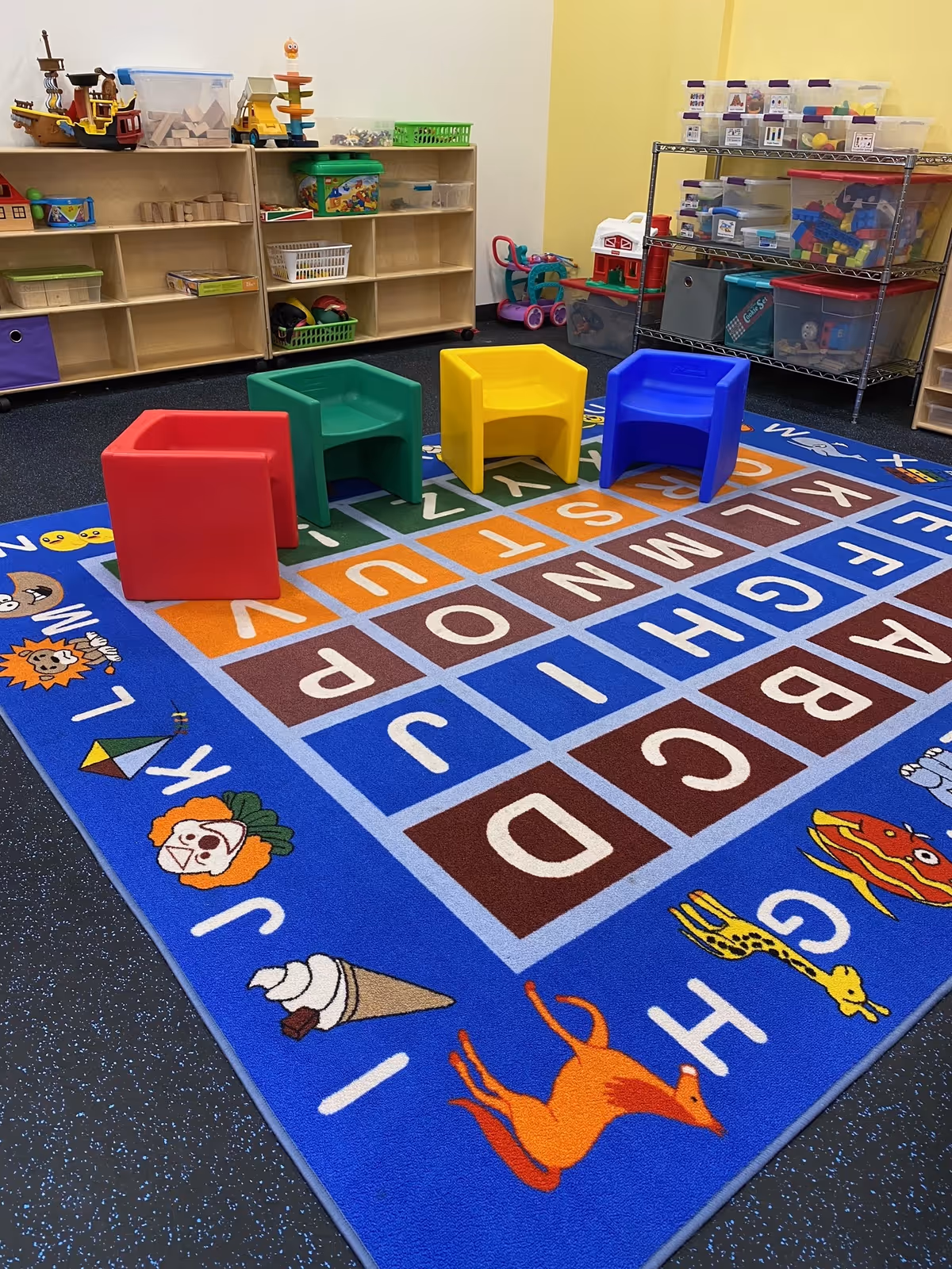 Colorful children's play area with small chairs and alphabet rug indoors.