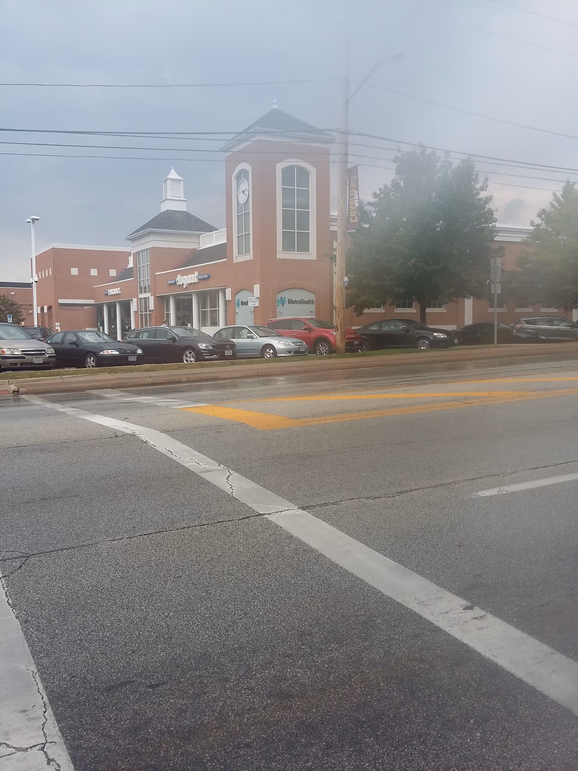 Brick storefronts of Discount Drug Mart with clock tower, parking lot, and a street in front.