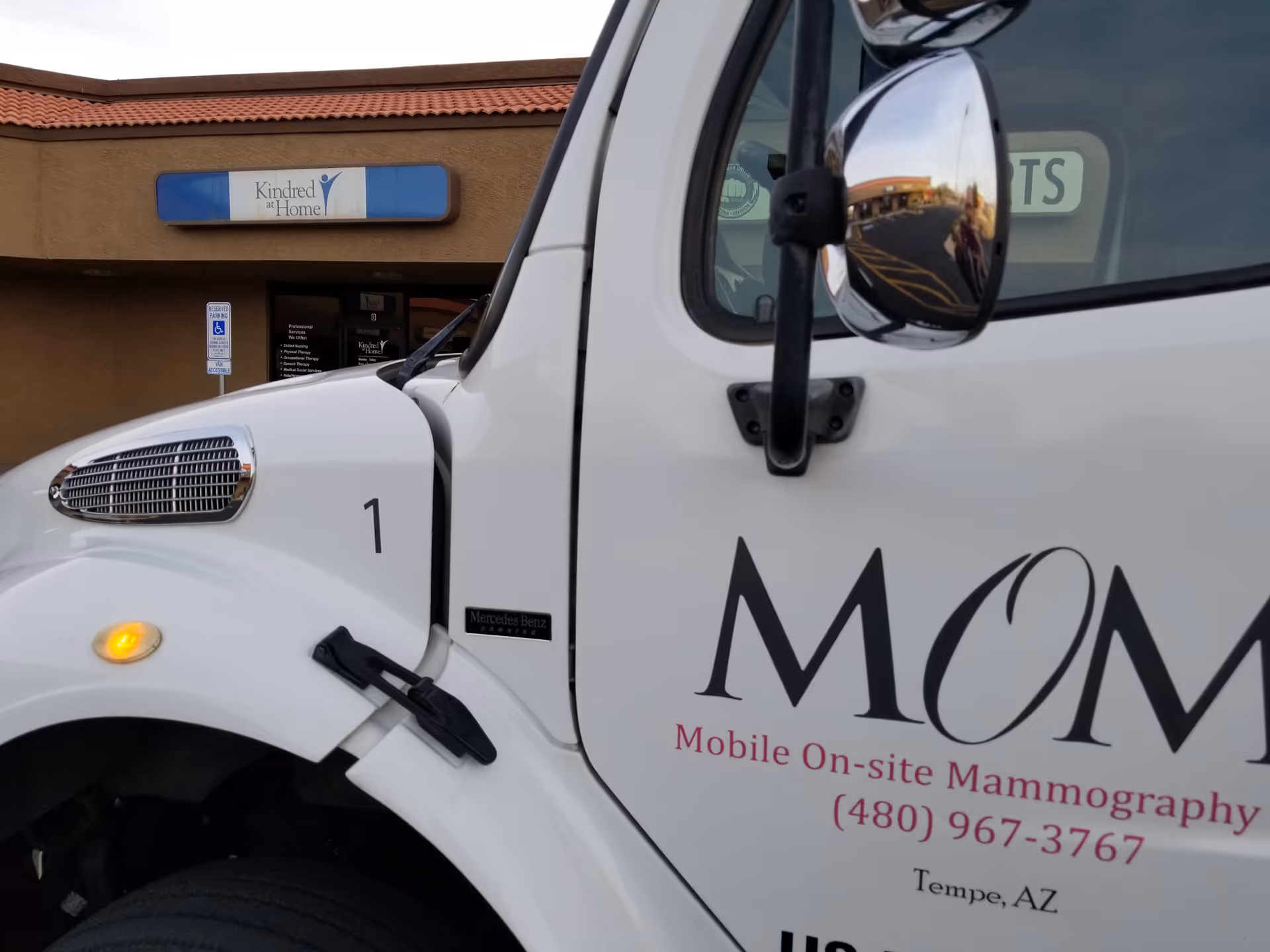 White mobile mammography van parked outside a senior care facility.