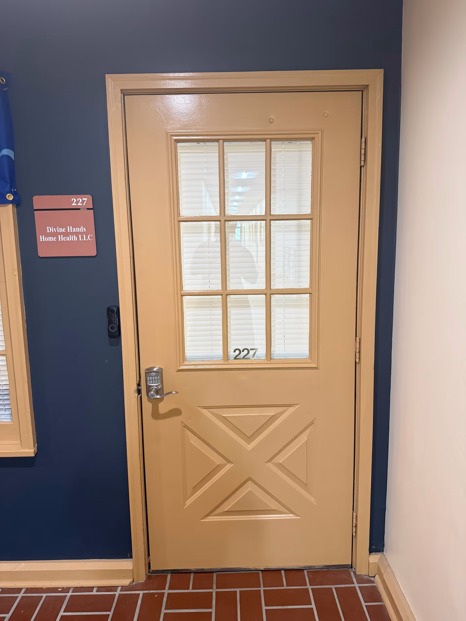 Beige door with glass panes labeled 227, in a dark blue interior hallway near a sign.