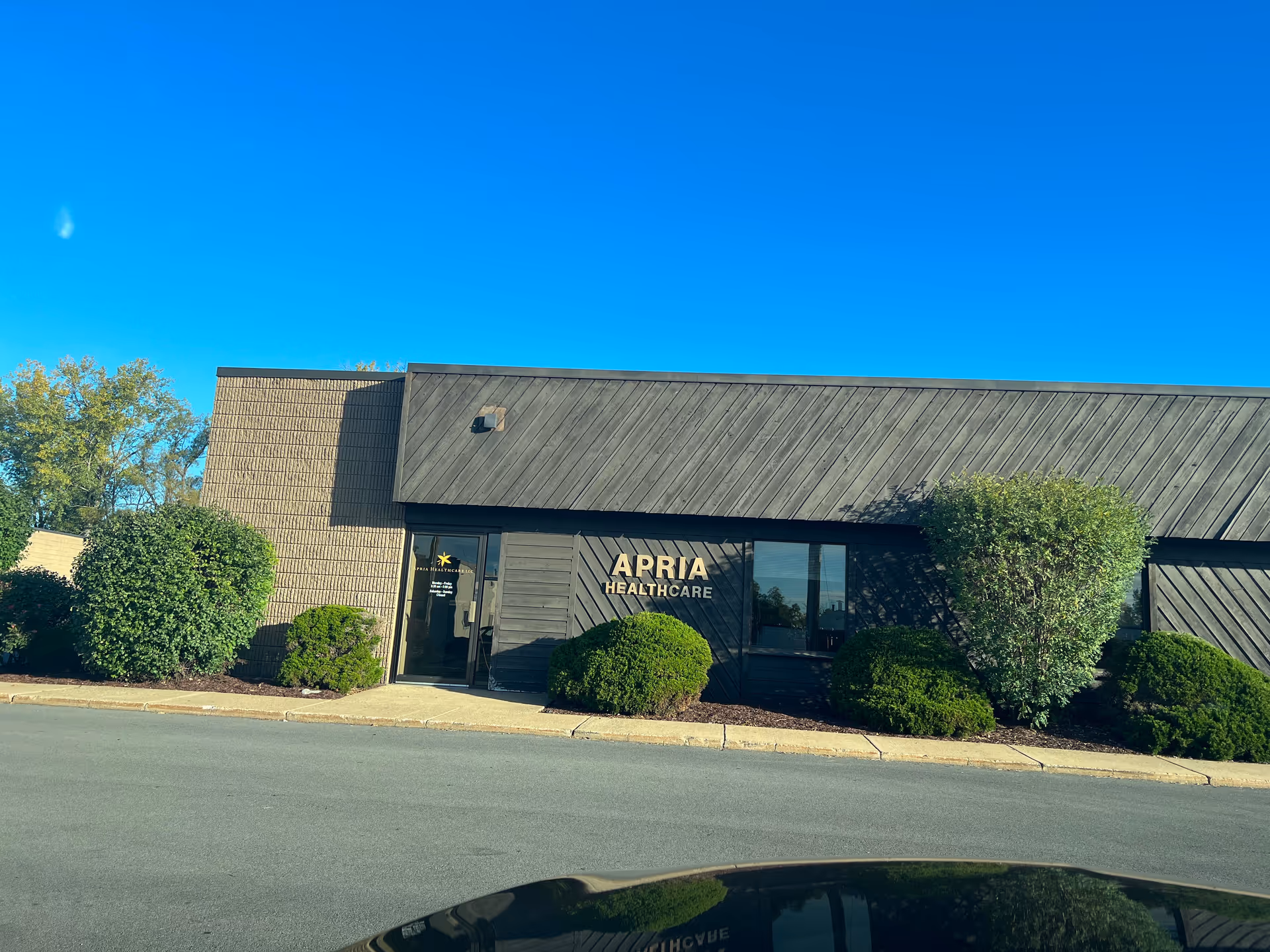 Front exterior of Apria Healthcare building with shrubs and blue sky