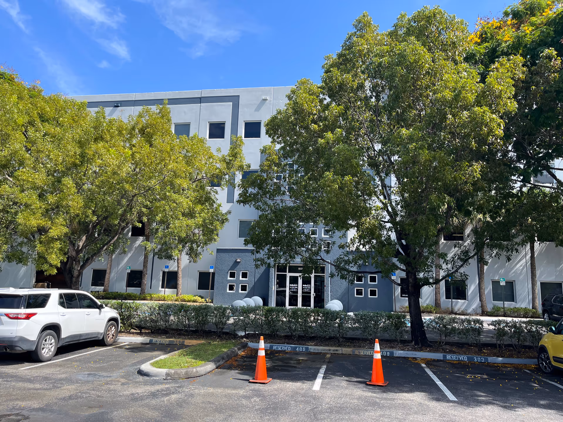 Exterior view of BrightStar Care facility front with gray facade, trees, and a parking lot.