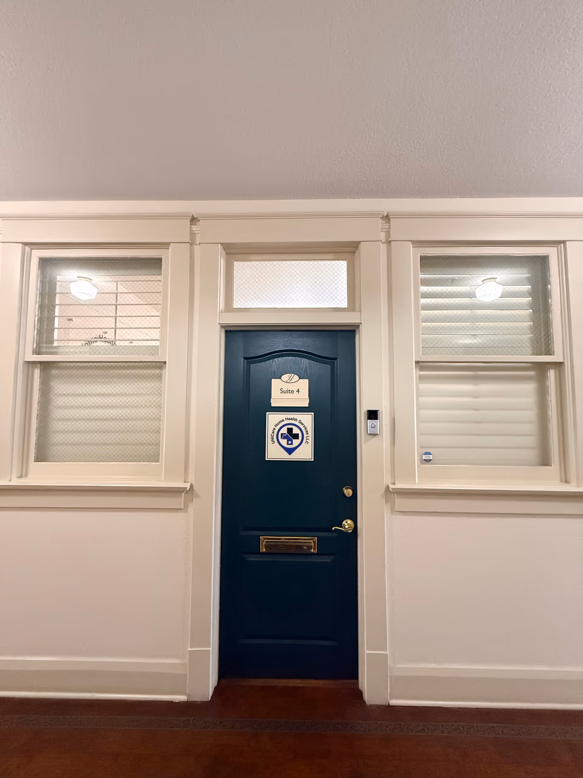 Blue door labeled Suite 4 between two windows in a white hallway.
