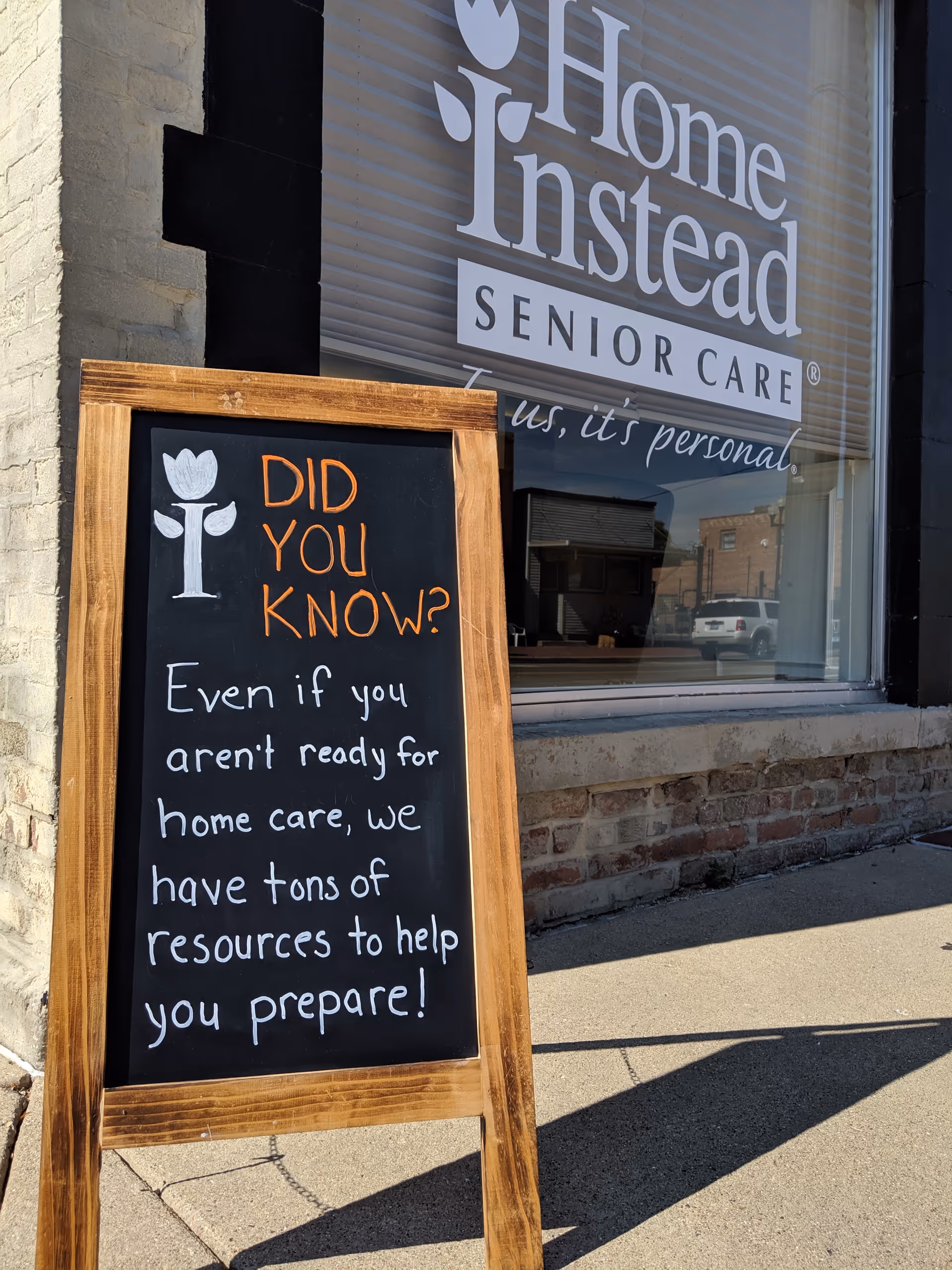 Home Instead Senior Care storefront with a chalkboard sign on the sidewalk outside