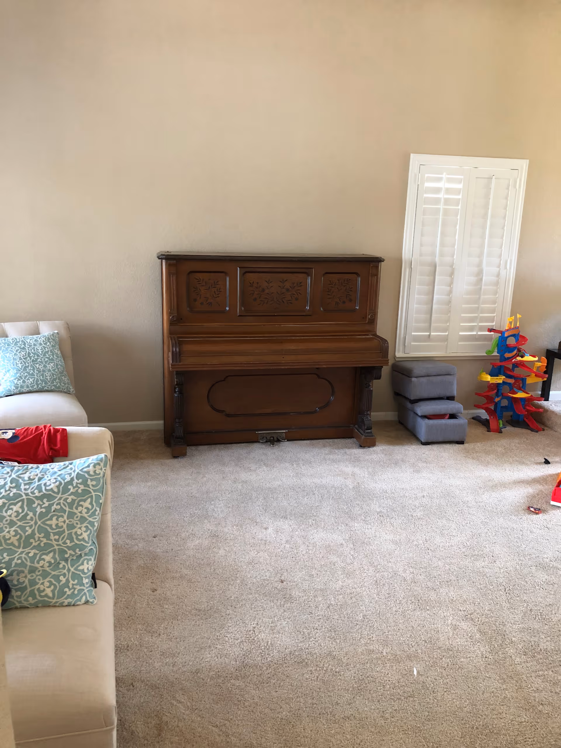 Cozy living room in a senior facility with a piano, sofa, and colorful toys.