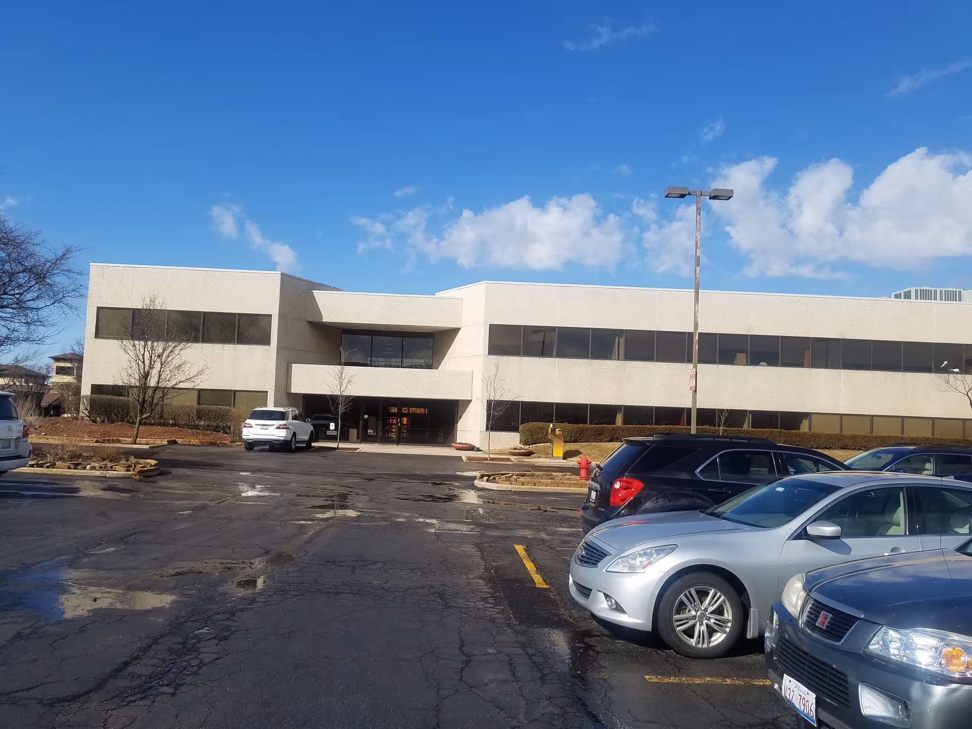 Two-story beige facility building with a parking lot and blue sky.