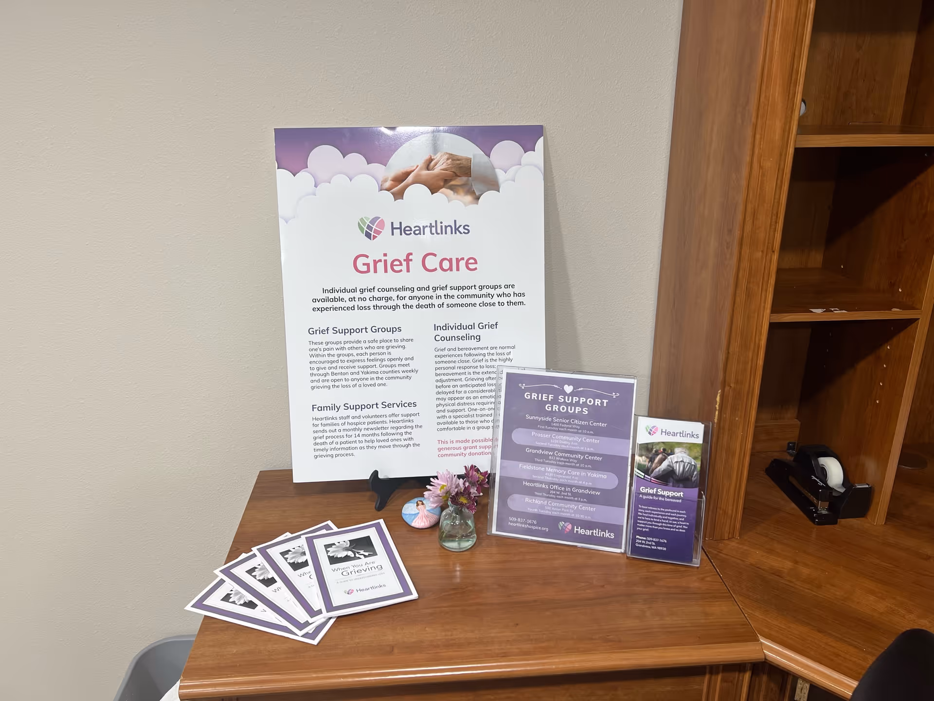 Indoor desk area with a Heartlinks Grief Care poster and brochures on a wooden counter.