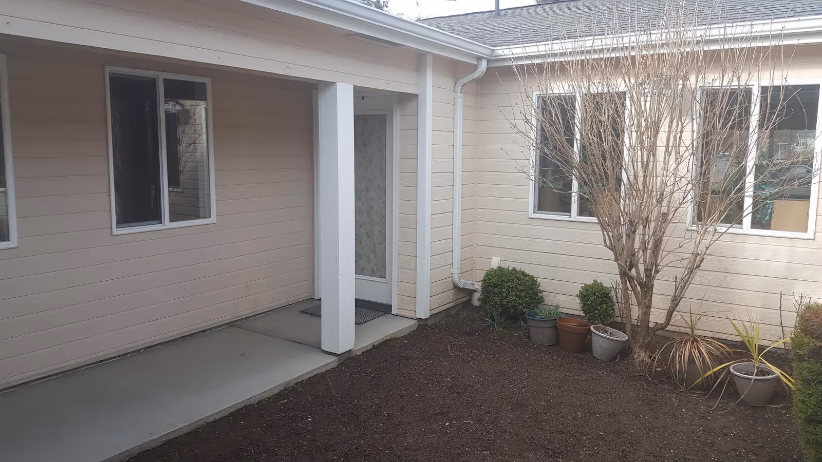 Exterior view of Heritage Home Care facility with entry door and potted plants.