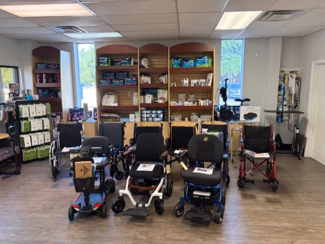 Interior room with mobility scooters and walkers arranged before shelves of supplies.