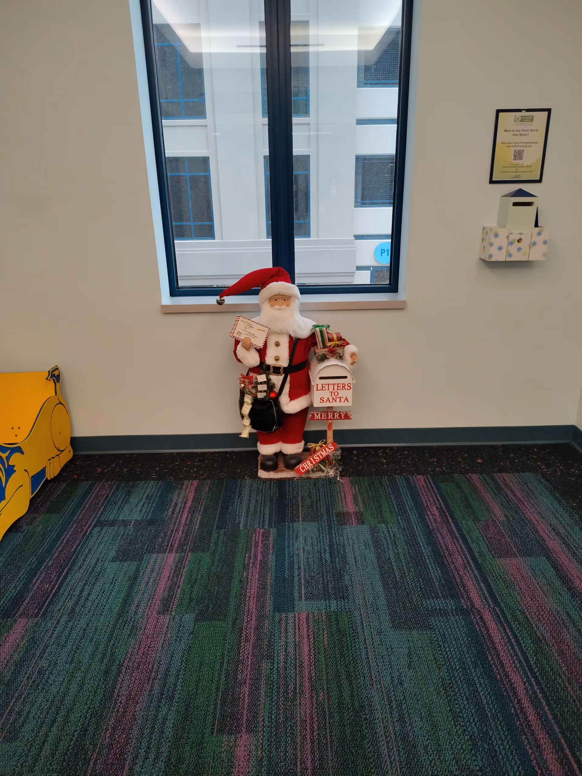 Decorative Santa Claus display in a hallway by a window.