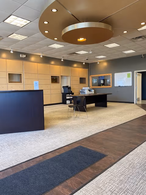 Modern reception area with wooden cabinets, desk, and circular ceiling feature in a spacious lobby.