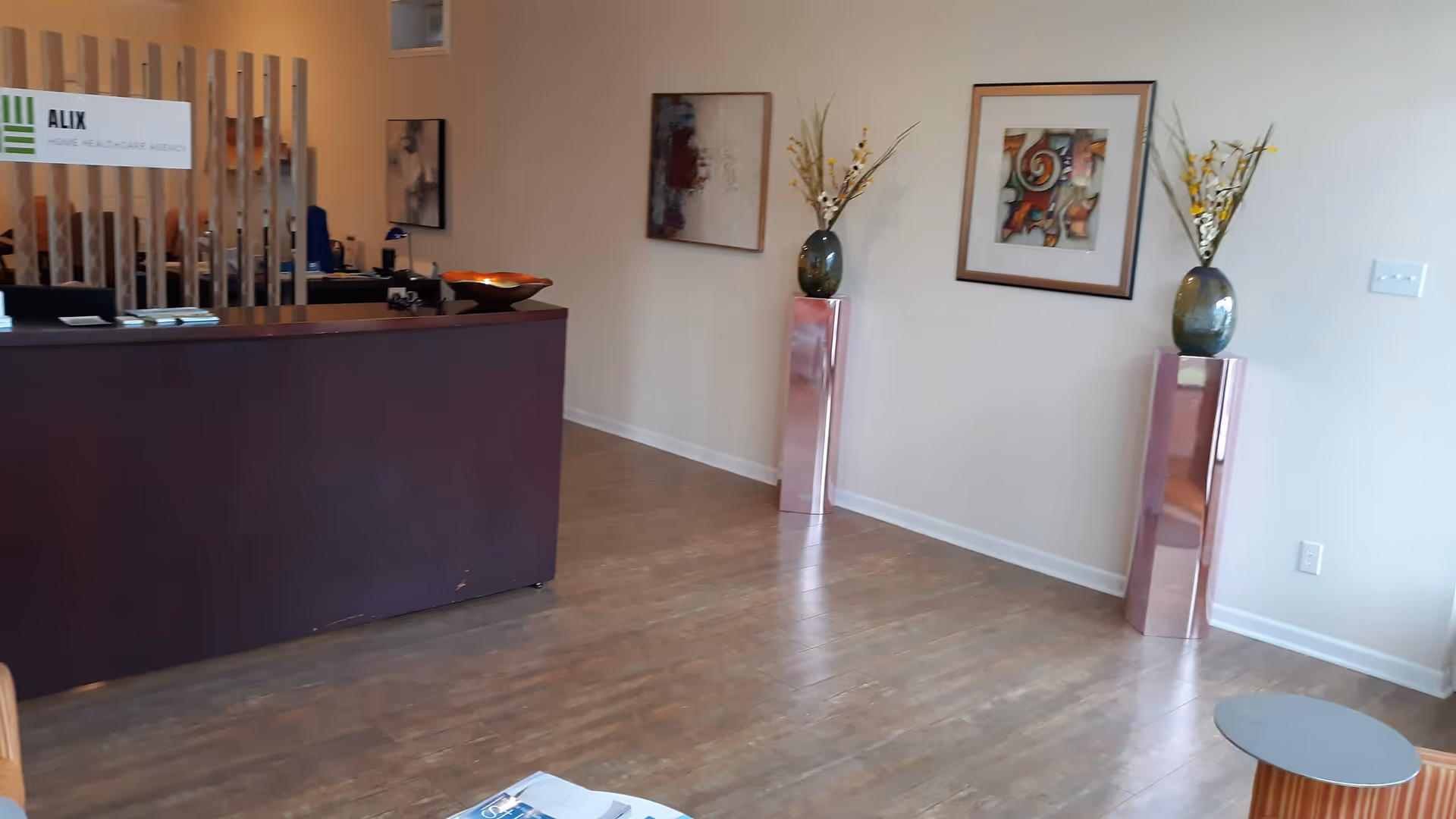 Reception desk in a modern senior care lobby with artwork and decorative vases.