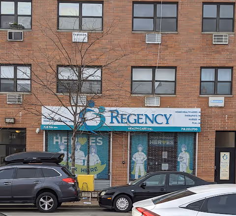 Brick building storefront for Regency Health Care with a blue sign and parked cars.
