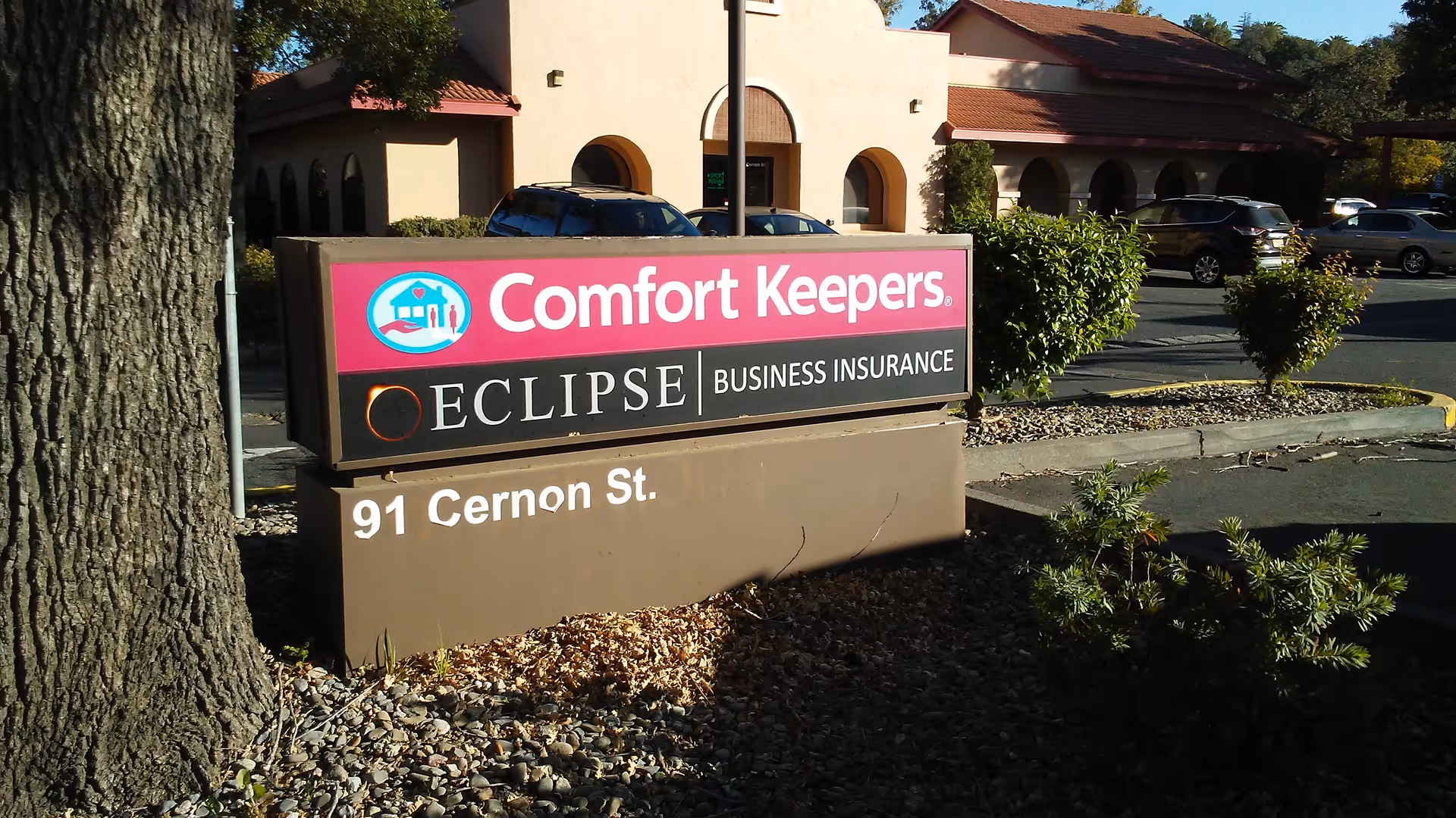 Outdoor sign for Comfort Keepers in front of a beige building with parking.