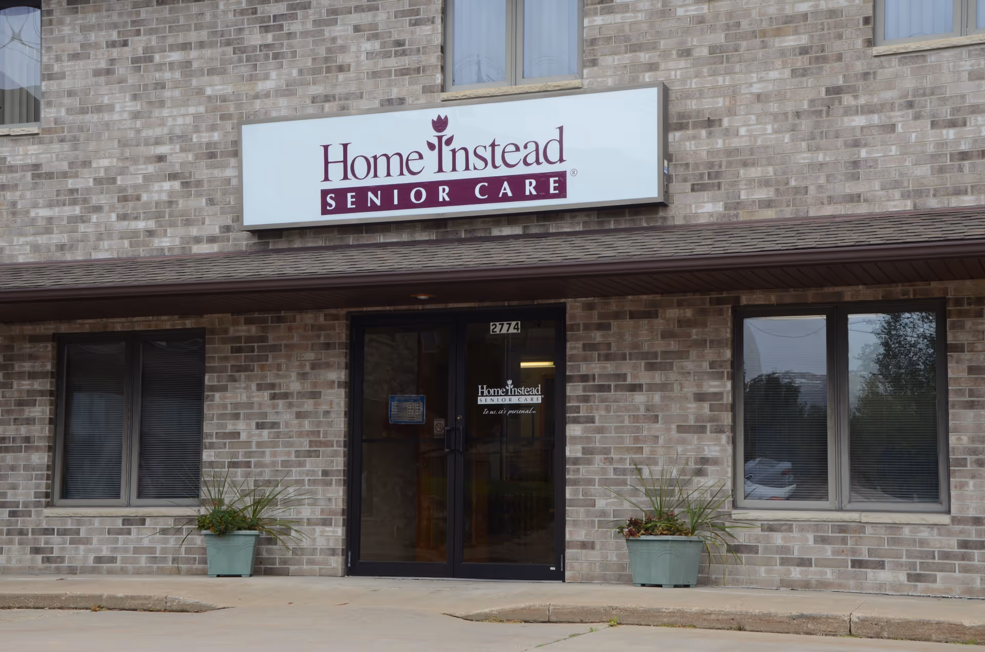 Brick building with Home Instead Senior Care sign and glass double doors at entrance.