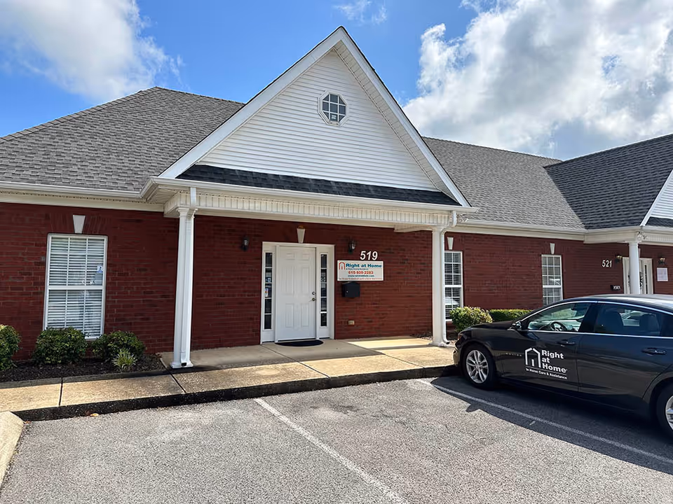 Front view of Right at Home senior care facility with brick exterior and a parked car.