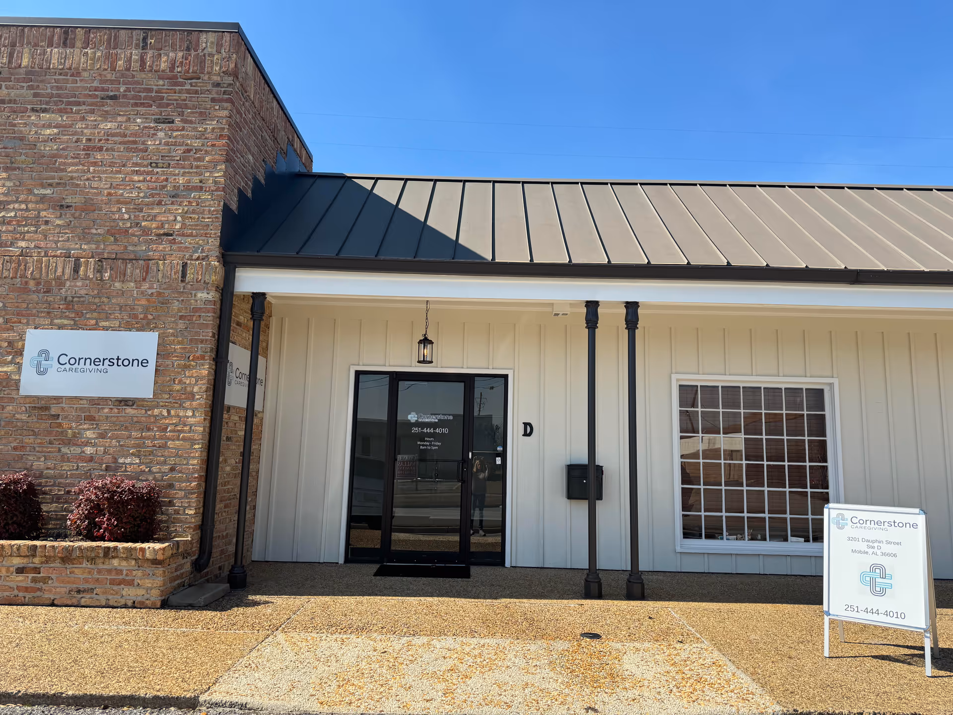 Front exterior of Cornerstone Caregiving building with sign and glass entry door.