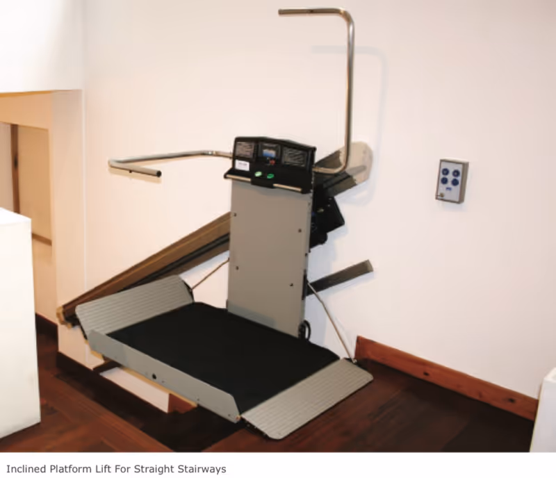 Inclined platform lift installed along a straight staircase in a hallway.