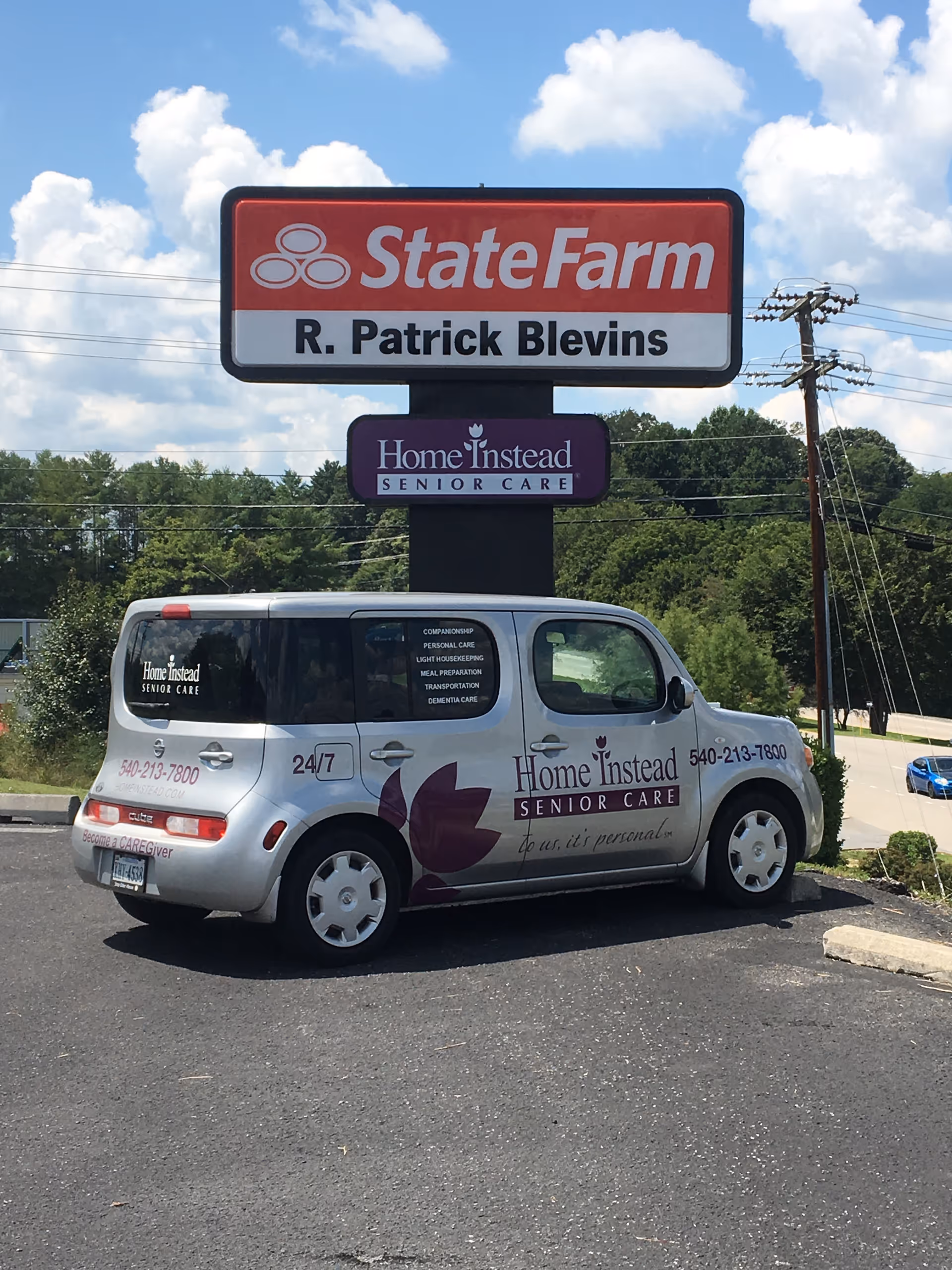 A white Home Instead Senior Care van parked in a lot beneath a State Farm sign.