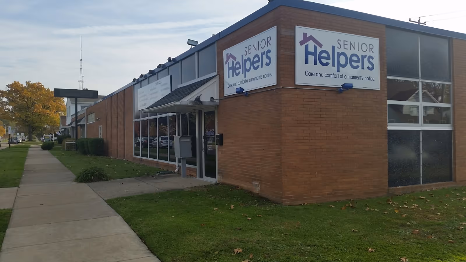 Exterior view of a Senior Helpers facility brick building with a prominent sign near the entrance.