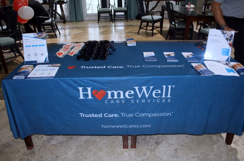 Blue HomeWell Care Services table with brochures in an indoor lobby area.