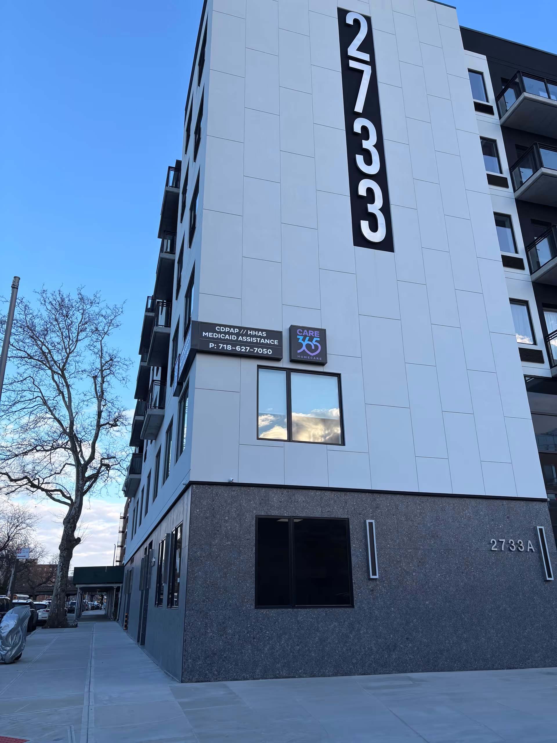 Modern multi-story exterior with vertical address panel and Care365 Homecare signage on blue-gray facade.