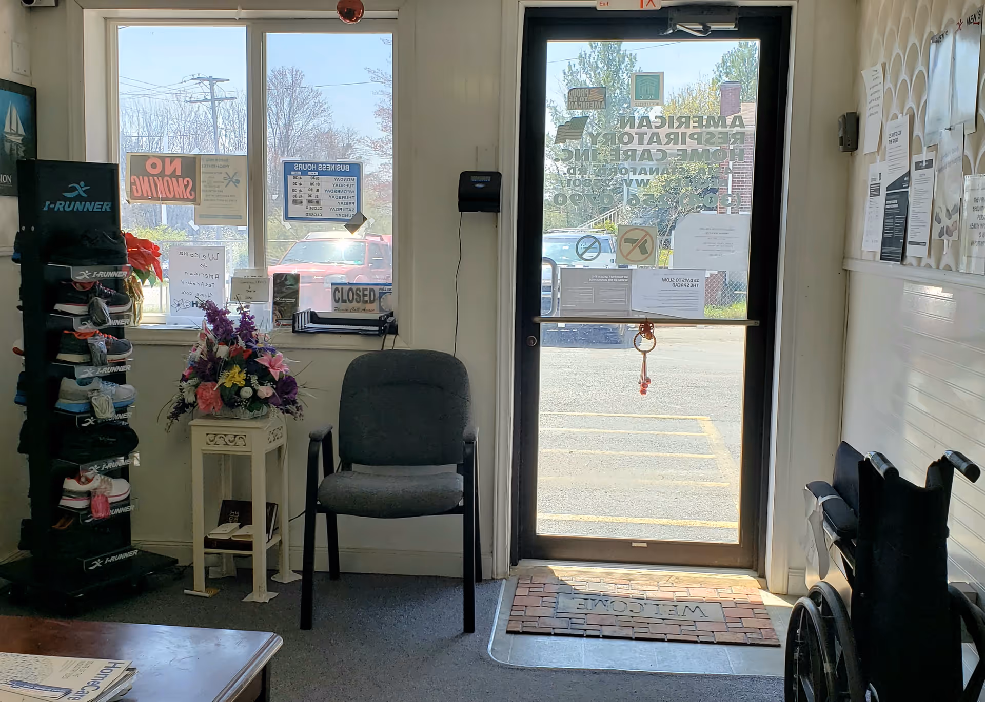 Interior facility lobby with a chair, shoe rack, flowers, and glass door.
