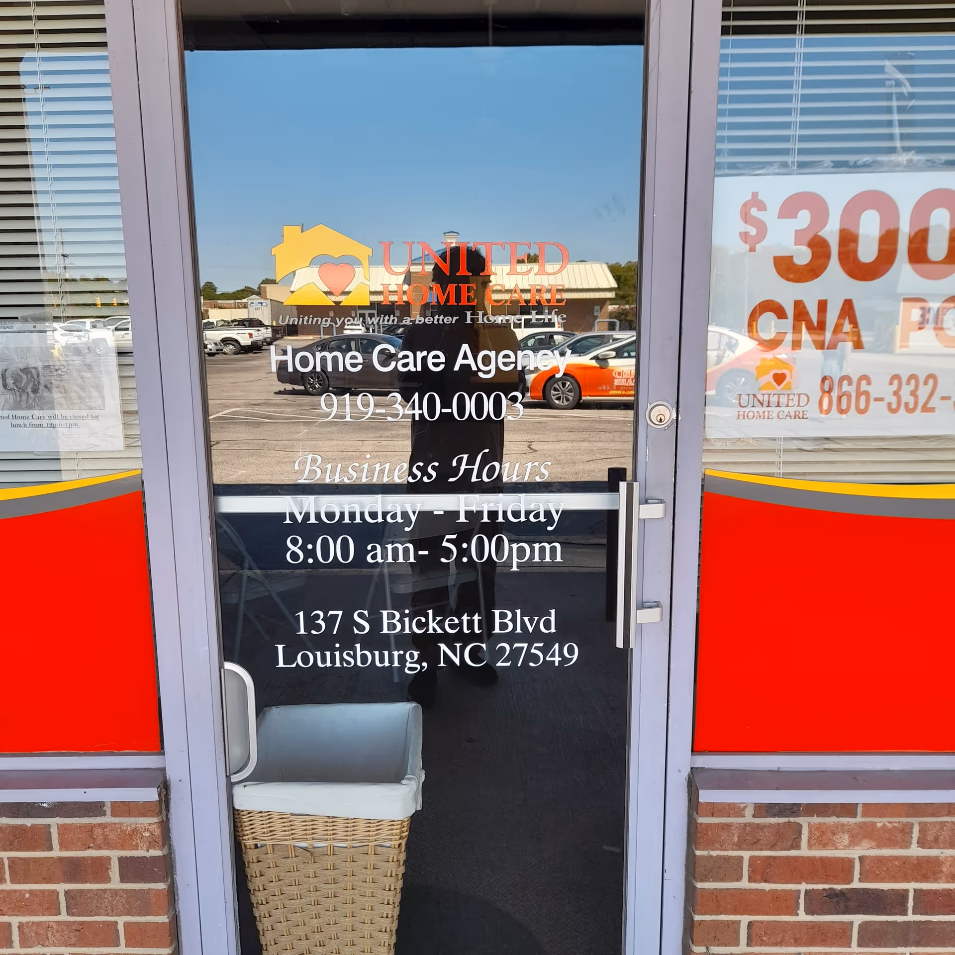 Glass storefront door shows United Home Care signage, hours, and address in Louisburg, NC.