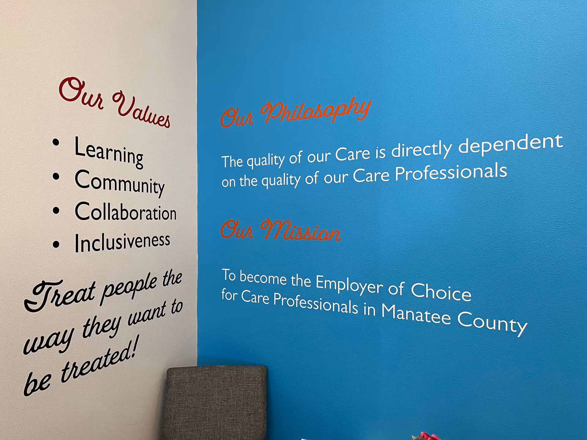 Interior wall displaying Our Values and Our Philosophy statements with a chair nearby.