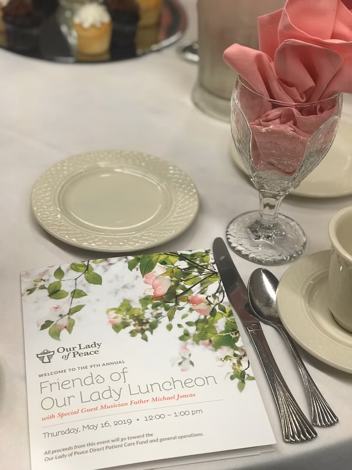 Close-up table setting inside a dining room with floral menu and pink napkins.