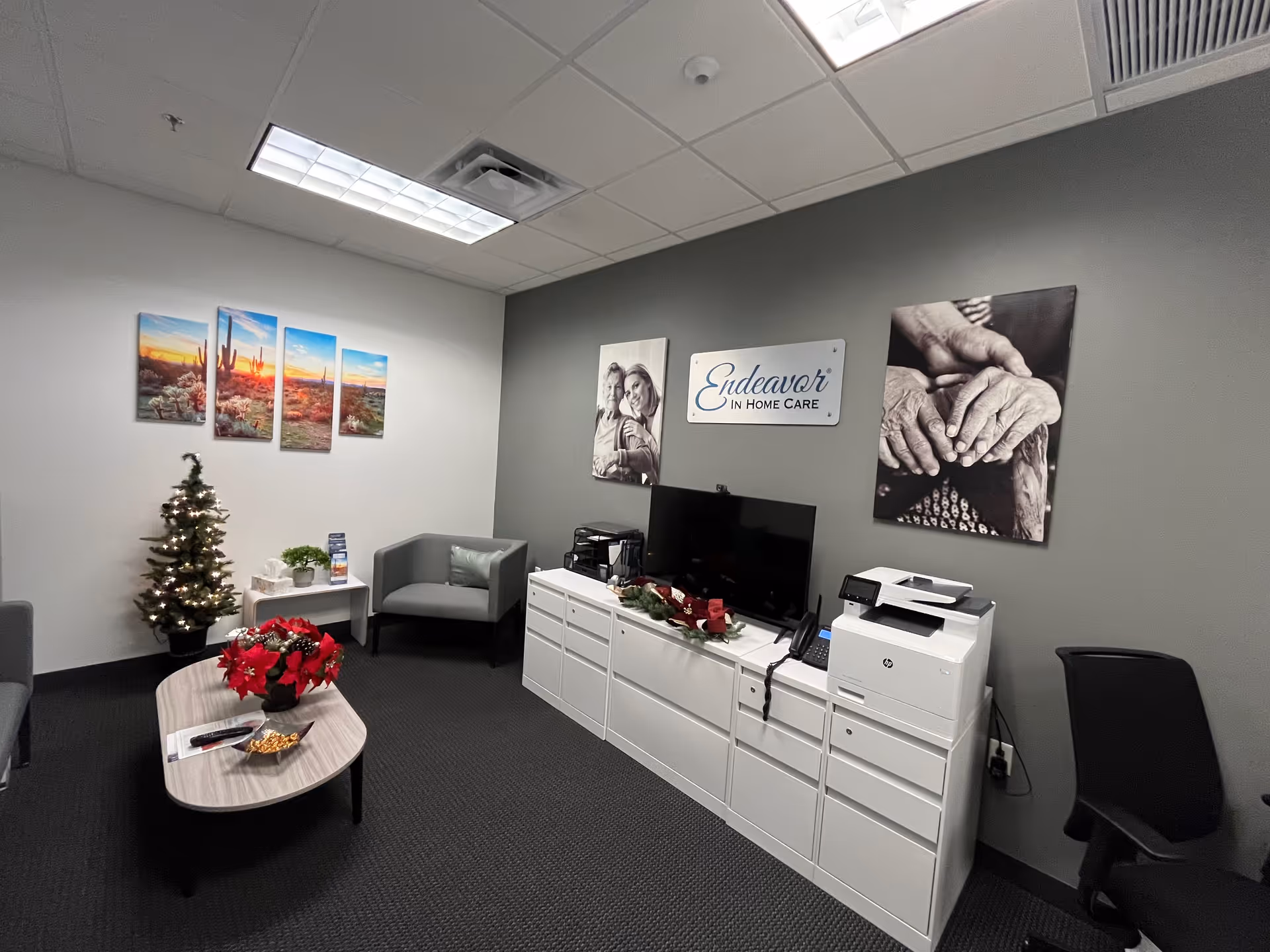 Interior reception area of Endeavor In Home Care with TV, cabinets, seating, and a Christmas tree.