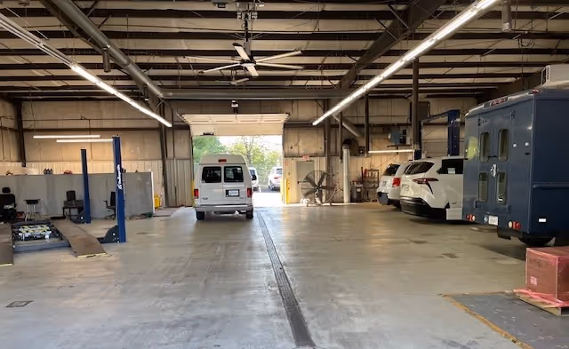 Industrial service bay with parked vans inside a large, well-lit workshop.