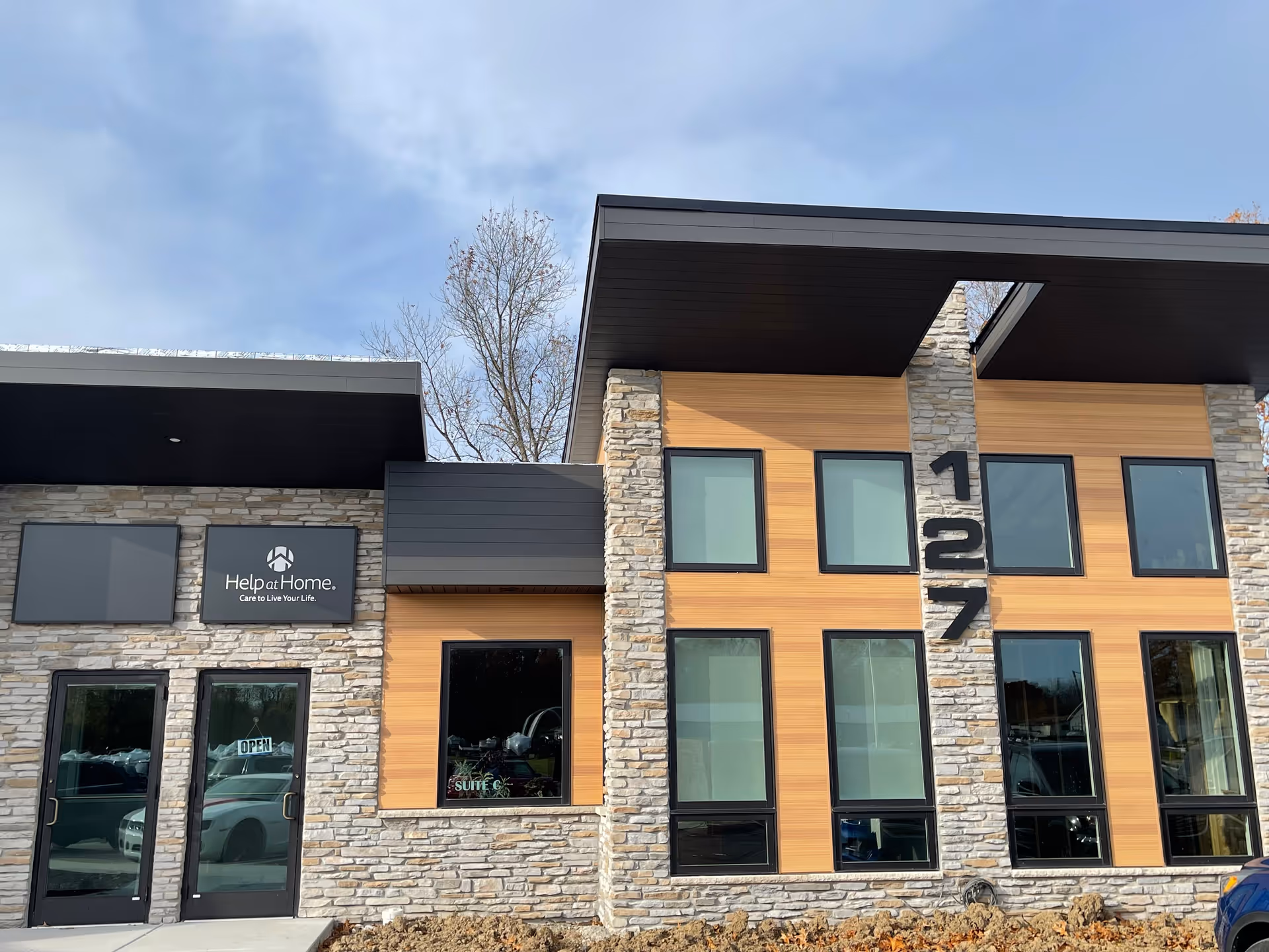 Modern senior living facility exterior with Help at Home sign and large glass windows.