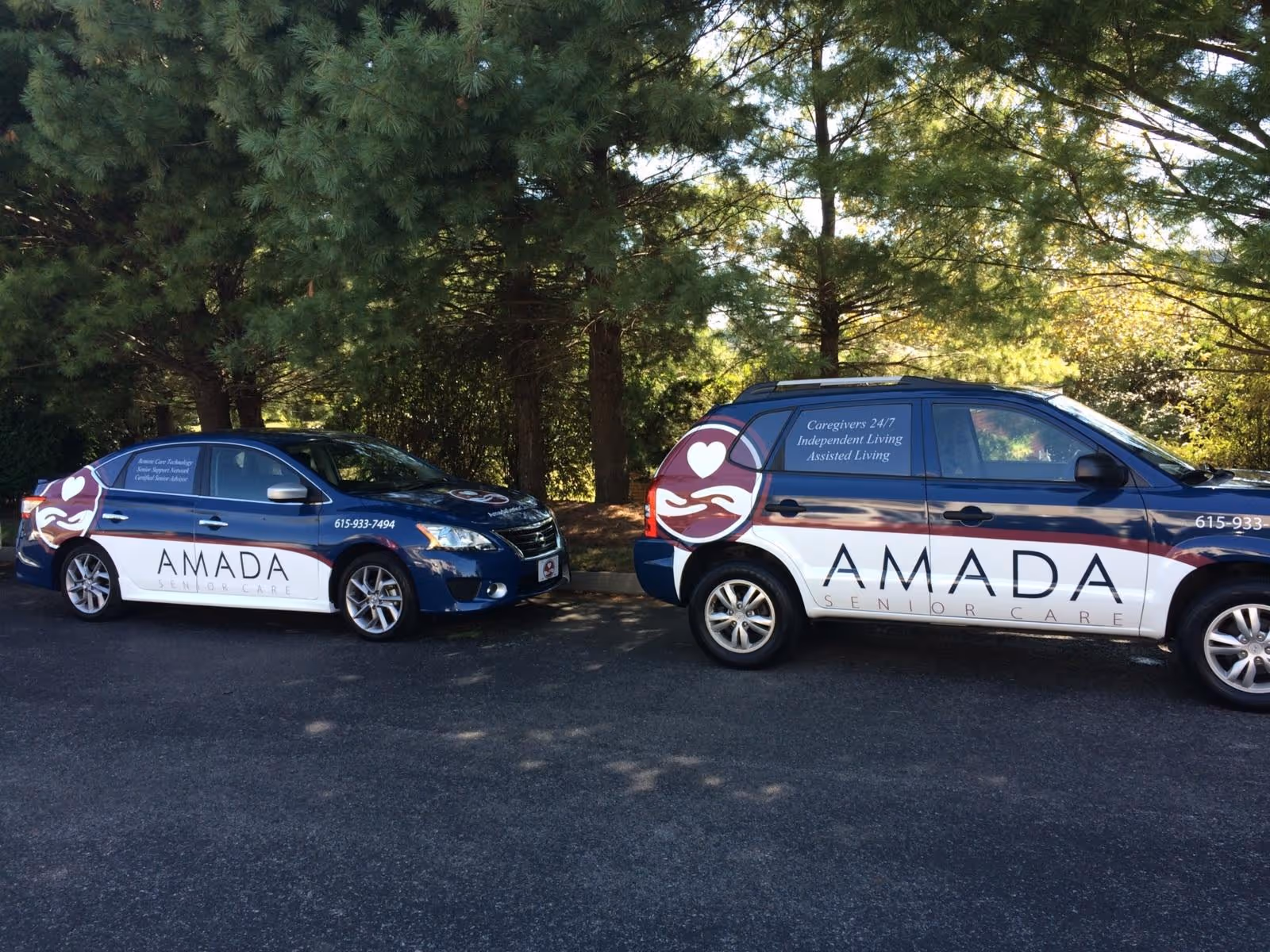 Two Amada Senior Care vehicles parked in a shaded outdoor lot.