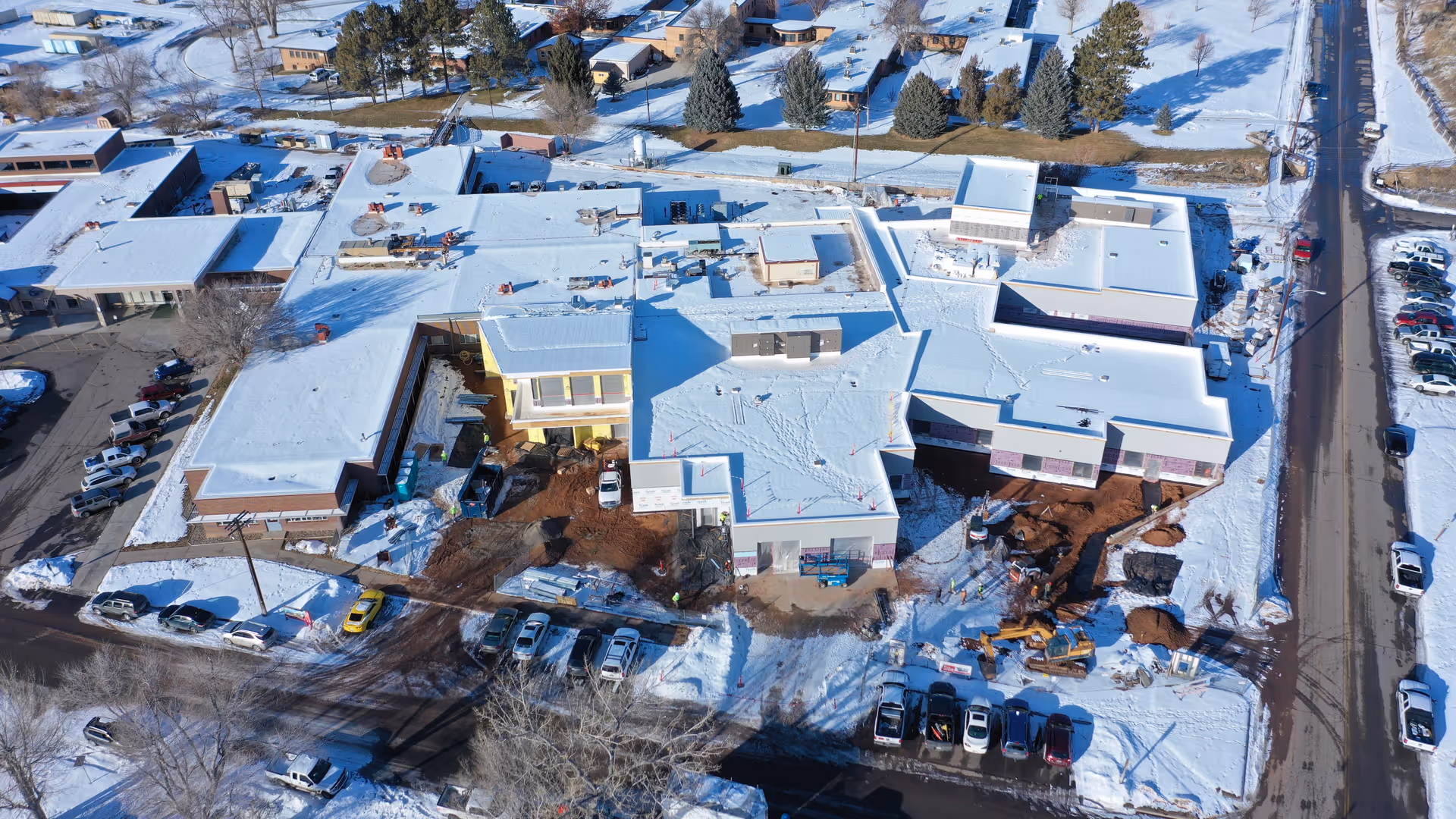 A snow-covered senior living facility campus viewed from above with parked cars.